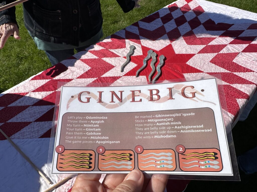 A hand holds out a laminated card detailing translated words in Ojibwe.