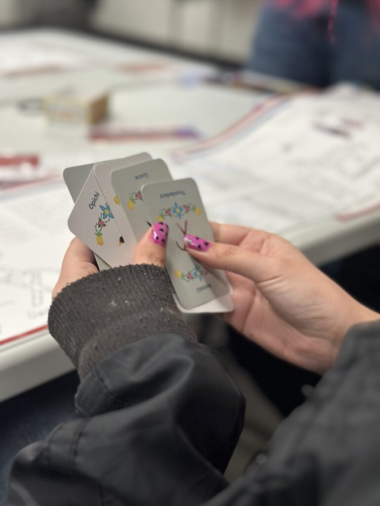 Hands with pink nails holding a deck of cards over a white table.