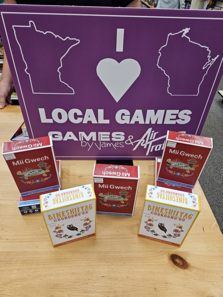 Game boxes laid out on a table in front of a sign that reads: I Heart Local Games."