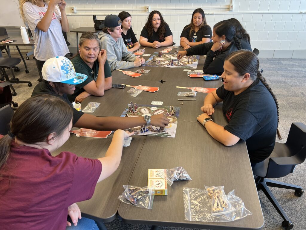 People sit around a table and play two card games.