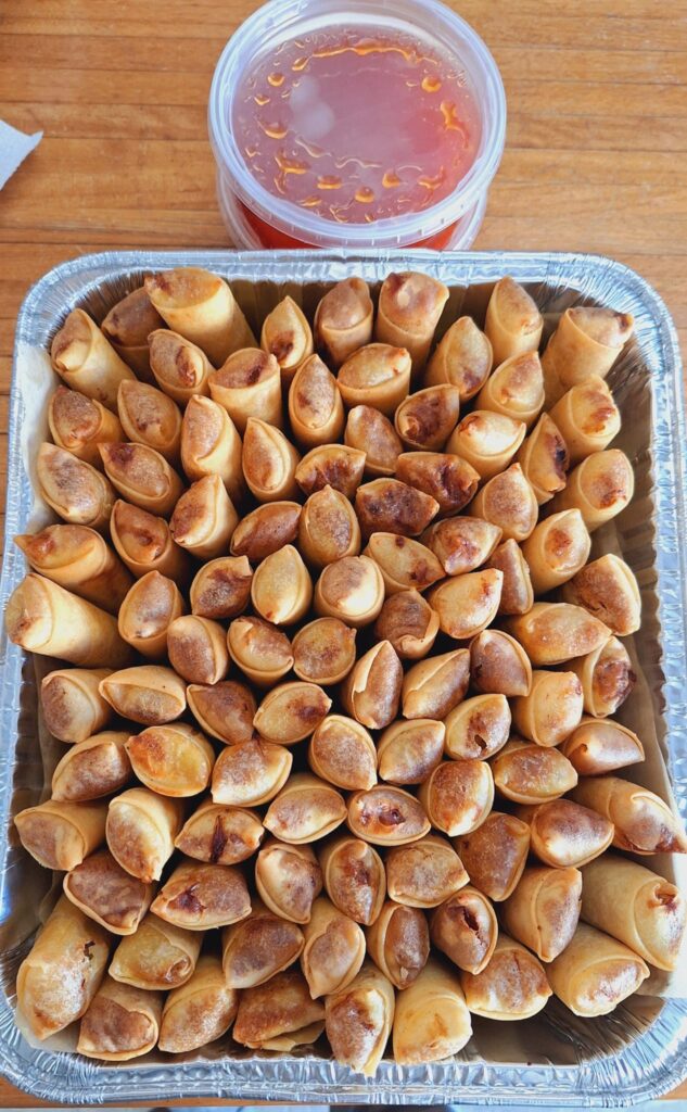 A silver tray filled with deep fried spring rolls.