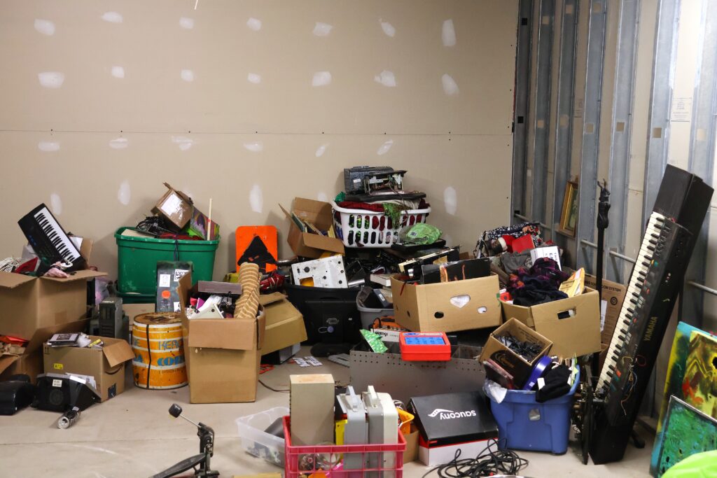 A room with boxes filled with electronics, cords, and musical instruments.