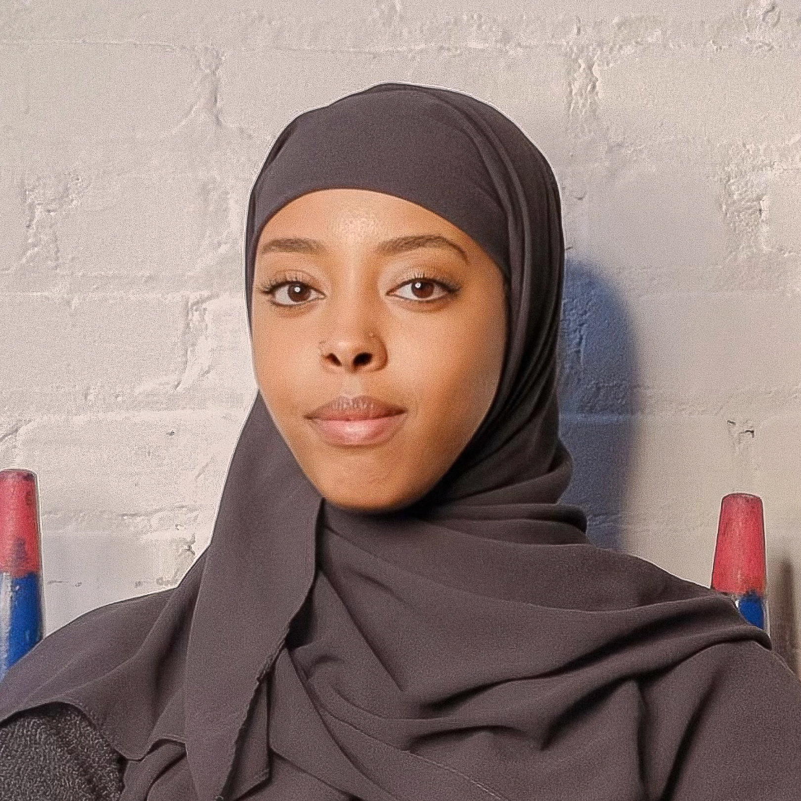 A person of medium dark skin tone wearing a dark brown hijab.