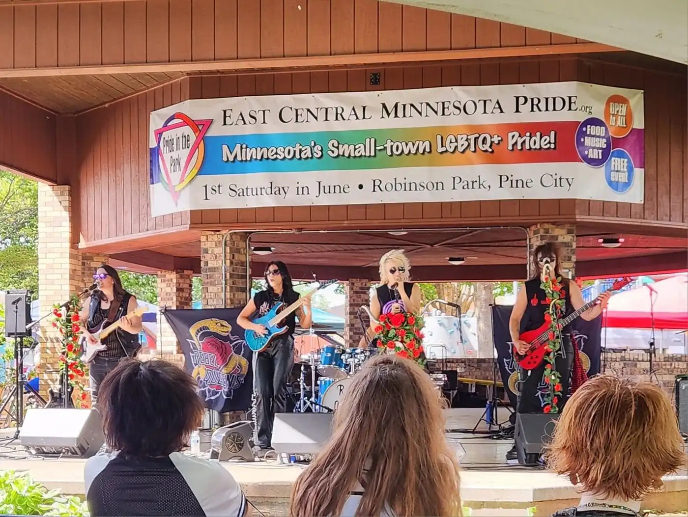 A four-member band performing at an outdoor bandshell.