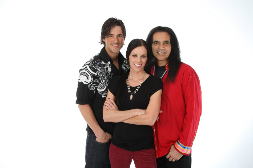 Three smiling people of medium-light skin tone with dark brown hair, in a posed portrait as a group.