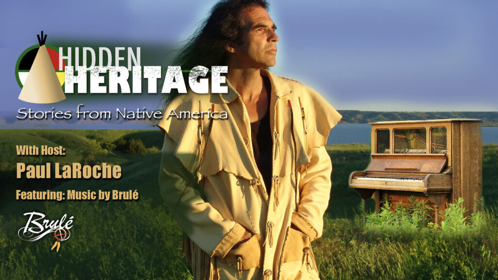 A person of medium skin tone and long dark hair standing outdoors on reservation bluff with an old upright piano in the prairie grass in background, with text reading, "Hidden Heritage: Stories from Native America, with host Paul LaRoche, featuring music by Brulé."