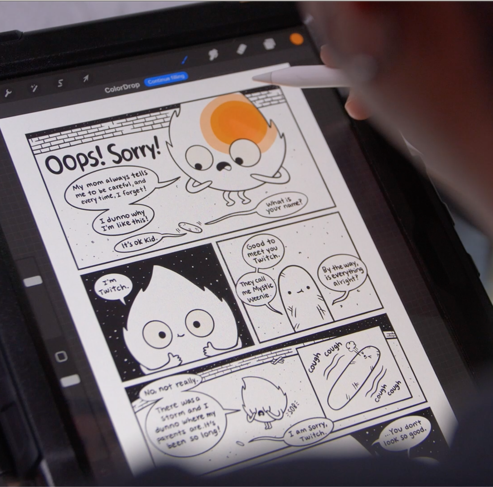 A hand holds a stylus and draws a comic on an iPad.