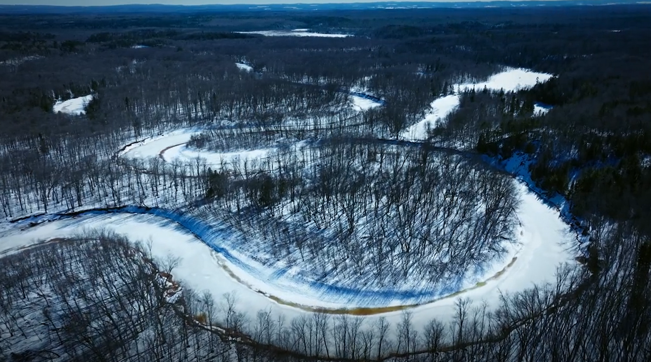 A drone image of a winding river through a winter landscape.