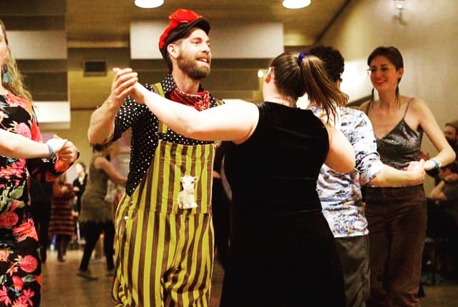 Couples hold hands and dance in a room together.