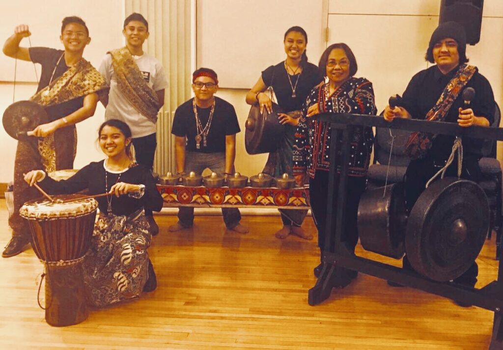 Seven smiling people with various traditional Philippine percussion instruments.