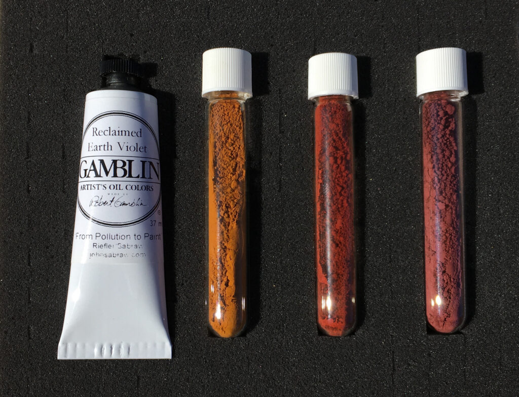 A tube of white paint next to three red/orange samples of pigments in tubes.