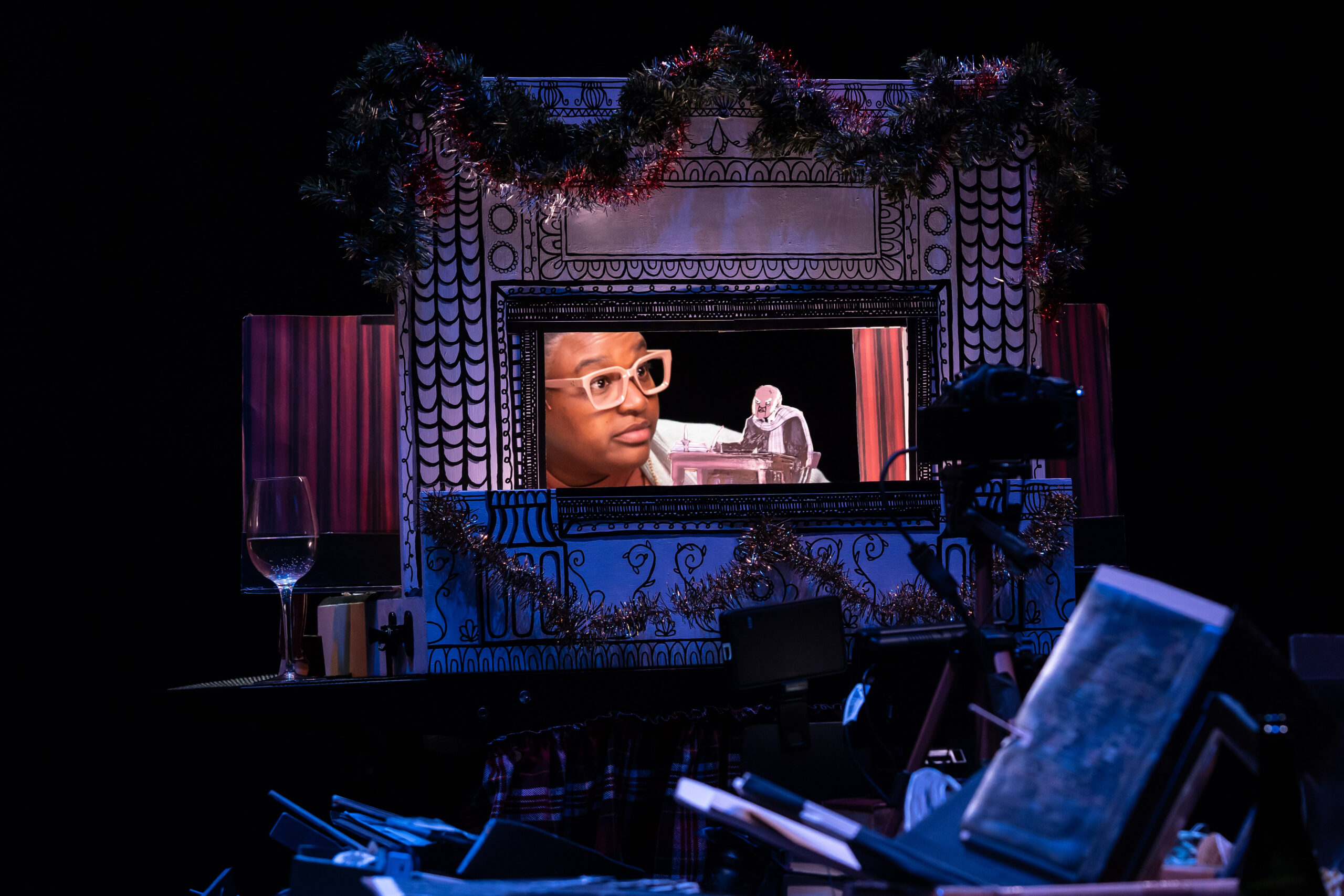 A miniature stage set with a paper cutout of a figure and an actor's head posed beside it.