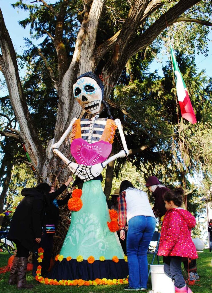 A large sculpture depicting a skeletal figure with colorful painted embellishments and flowers.