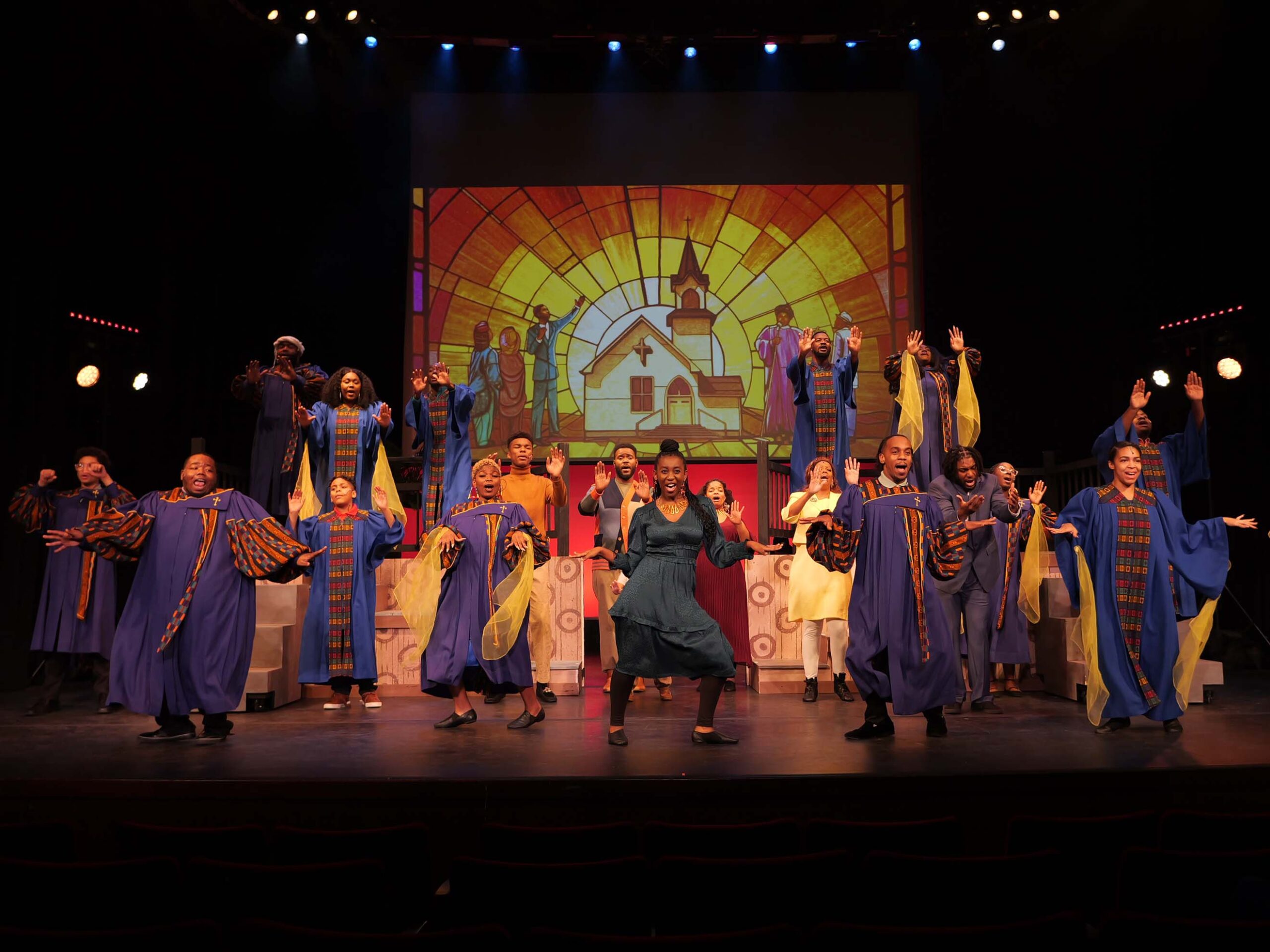 Black chorus members performing on stage in front of a church themed stained glass backdrop