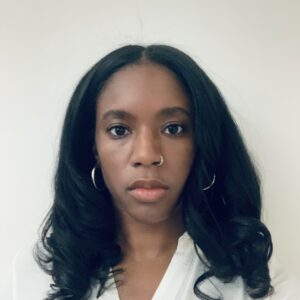 Headshot of a Black woman with medium skin tone and shoulder-length black hair, wearing a white blouse.