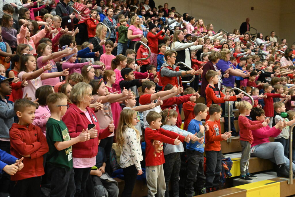 A large crowd of students all give the thumbs up sign.