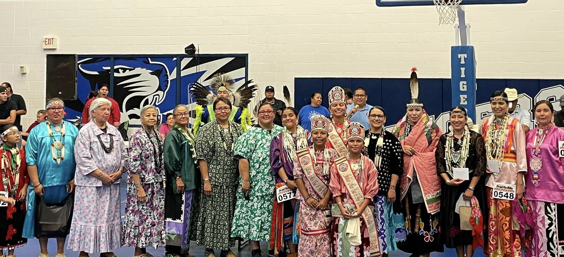 A large of group of people wearing traditional regalia line up.