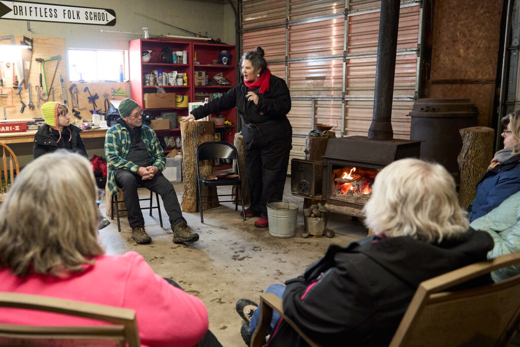 A circle of seated people watch as an instructor talks to them.