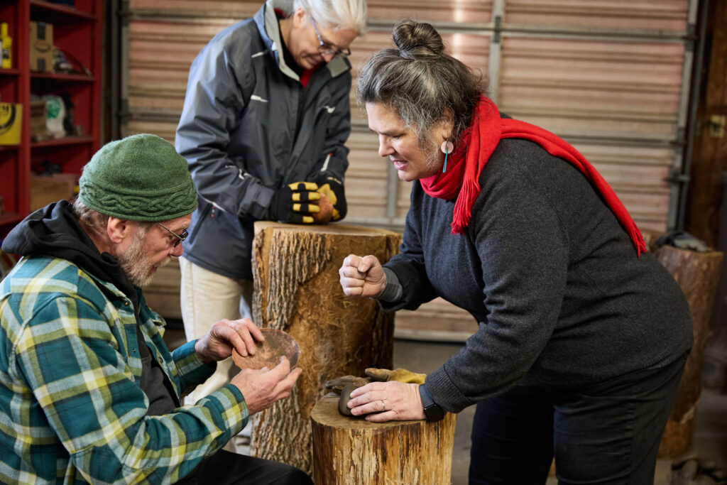 An instructor showing a student a bowl-making technique.