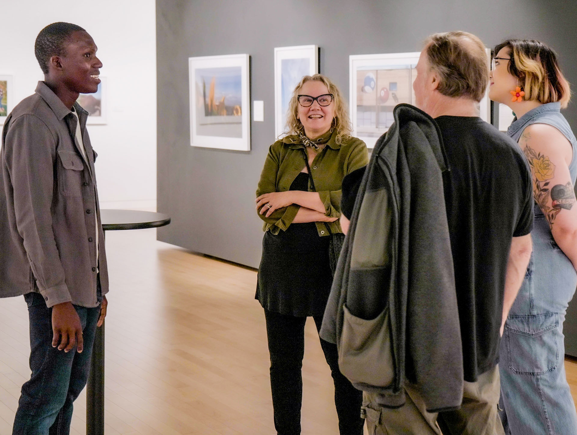 Light-skinned woman smiles amid three other people in an art gallery.