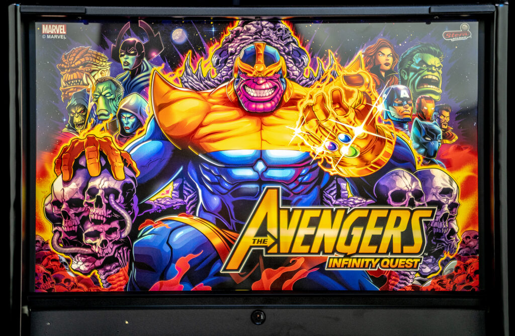 Backglass artwork from Stern's Avengers: Infinity Quest pinball machine, showing Thanos holding the Infinity Gauntlet surrounded by Marvel heroes and cosmic villains in a bold, comic book style.
