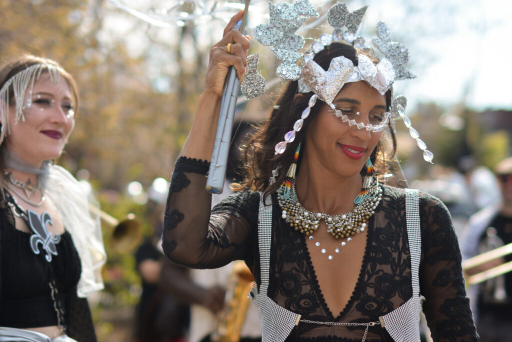 A medium-skin-toned person donned in silver adornments dances.