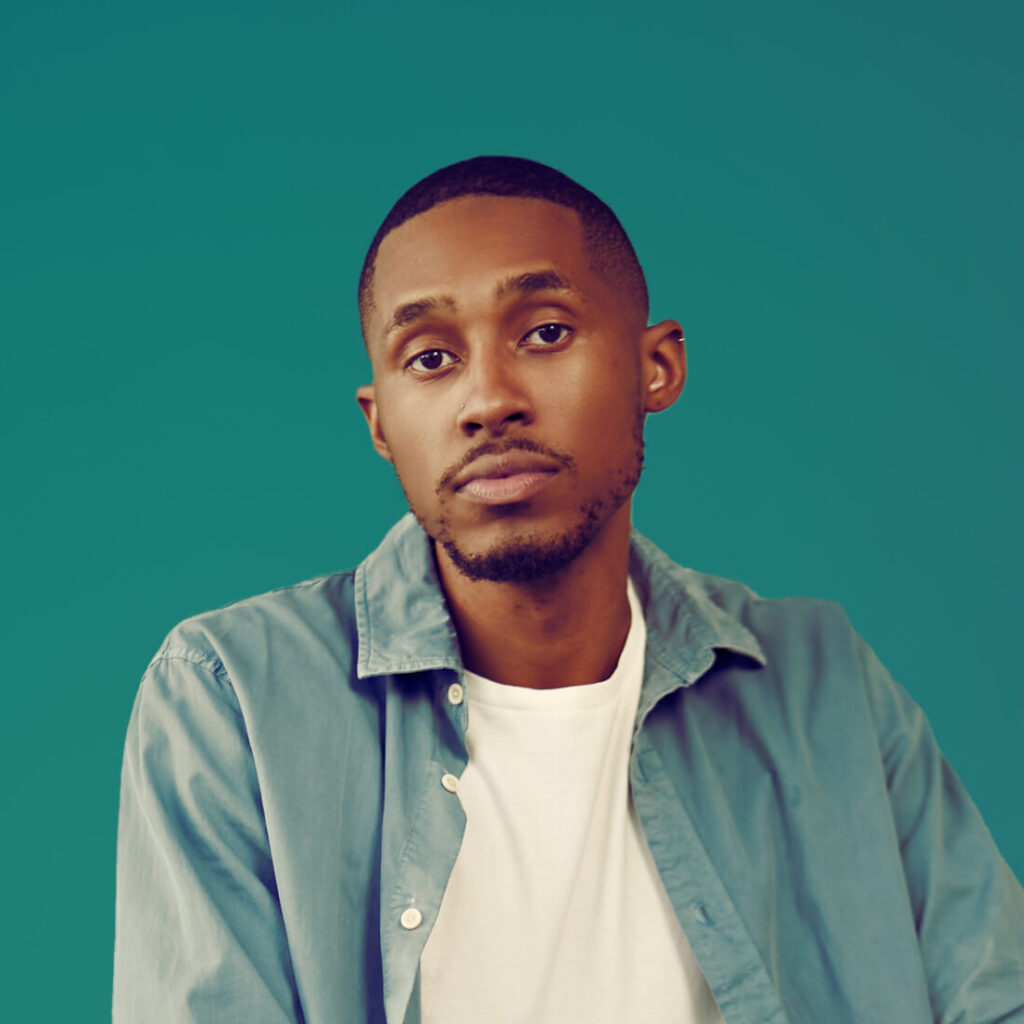 Portrait of a person with brown skin tone and short hair, wearing a teal button up and white shirt, on a teal background.