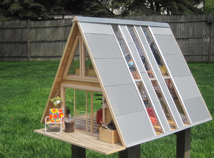 A miniature A-frame style house with miniature furniture and design details