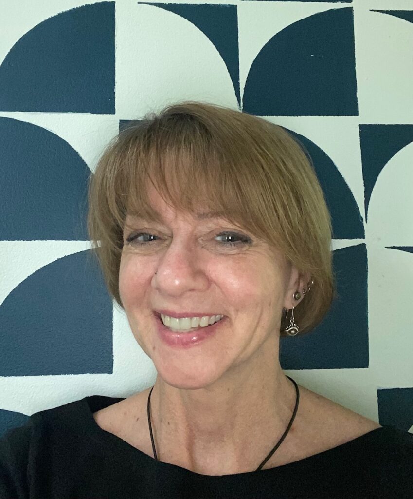 A person of light skin tone with a short bob hair style wearing a dark top.