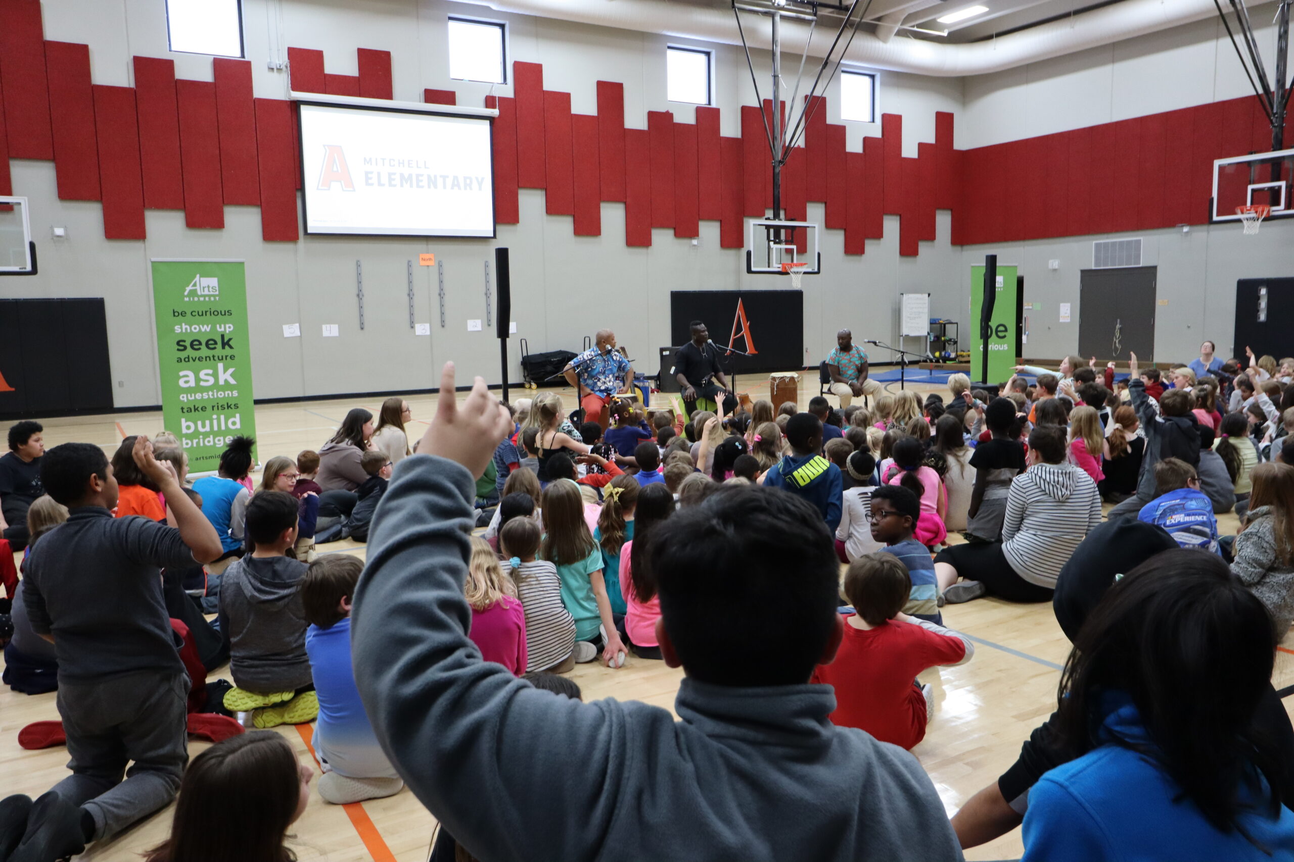 Students raising hands in auditorium
