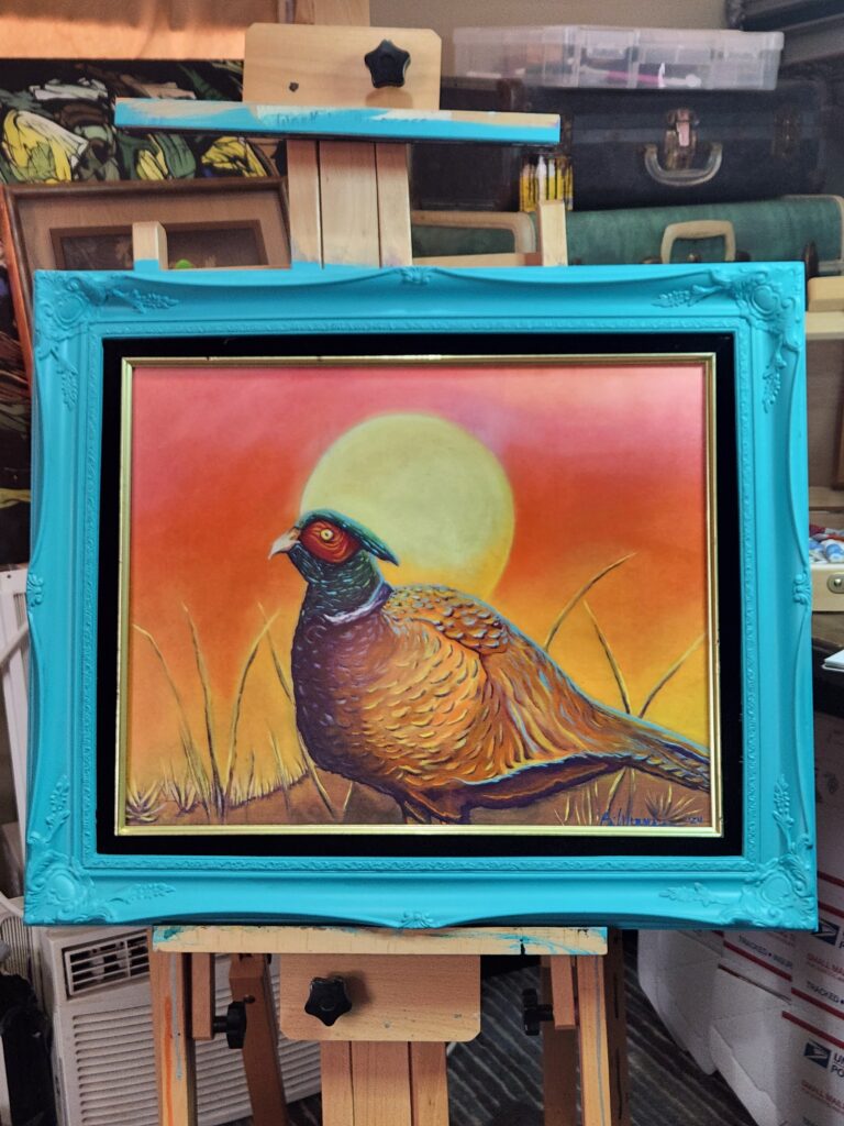 A plump pheasant with golden-brown feathers, a green head, and a large red patch over its eye standing amid tall strands of grass with a large yellow sun blazing behind it in an orange sky.