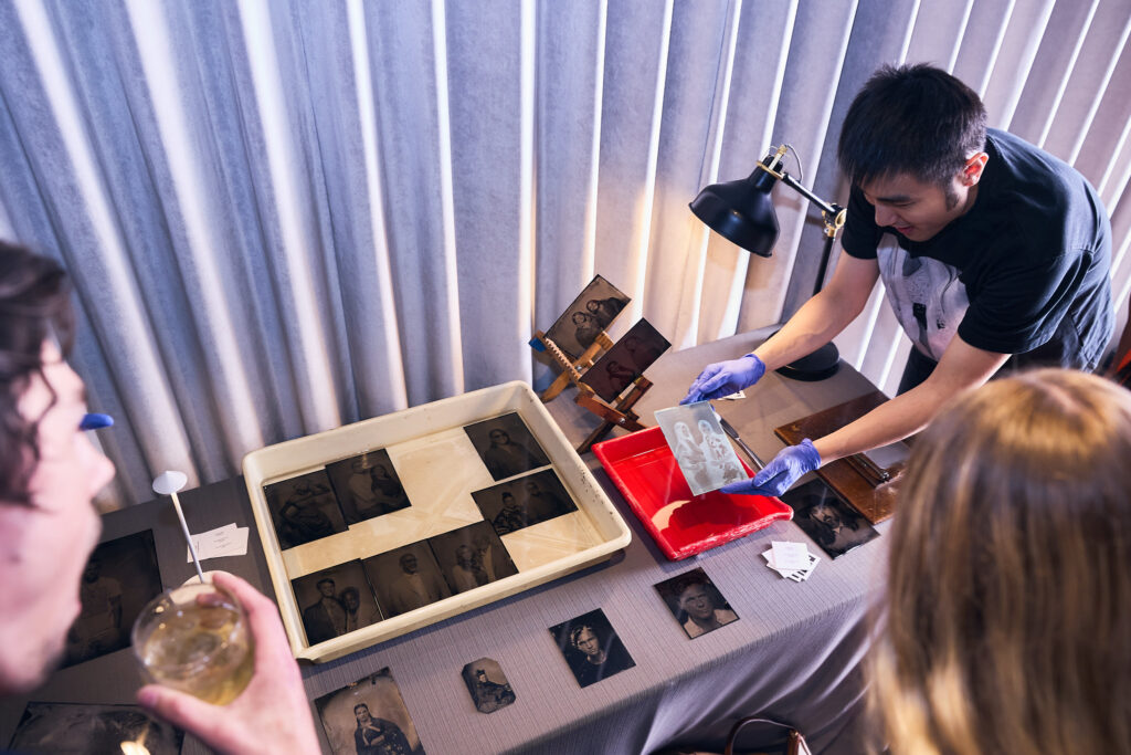 A person does printing of photos in front of an audience.