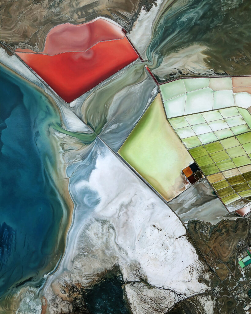 An abstract aerial landscape resembling large bodies of water richly colored in blues, greens, and reds, enclosed by human-made barriers near tiny human settlements.