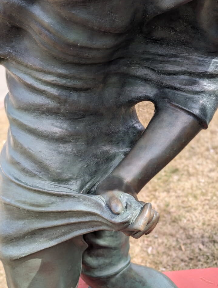a closeup of a bronze statue person's hand wrapped in fabric.