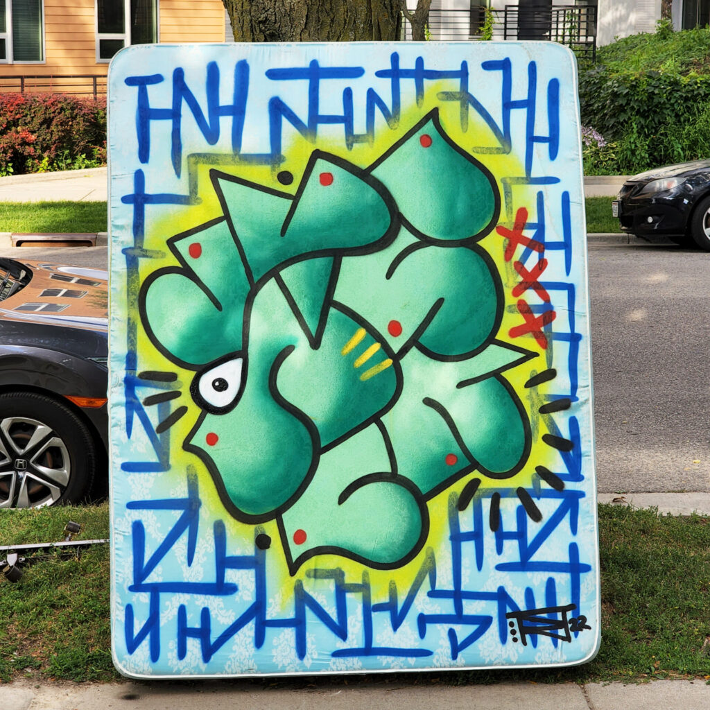 A white mattress with green abstract art painted on it.