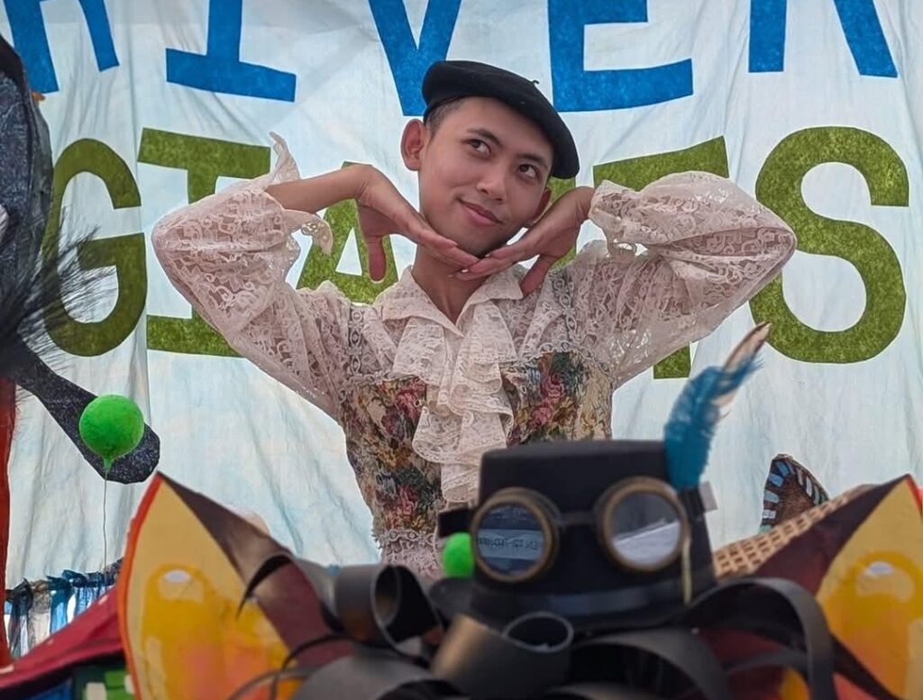 A person with medium skin tone smiling and posing for a photo.