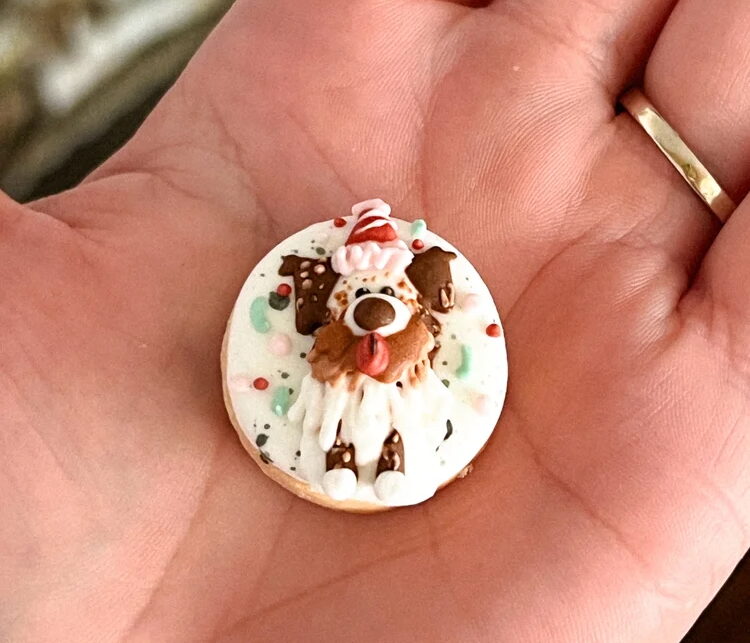 A light skinned palm holding a small cookie with decorated icing.