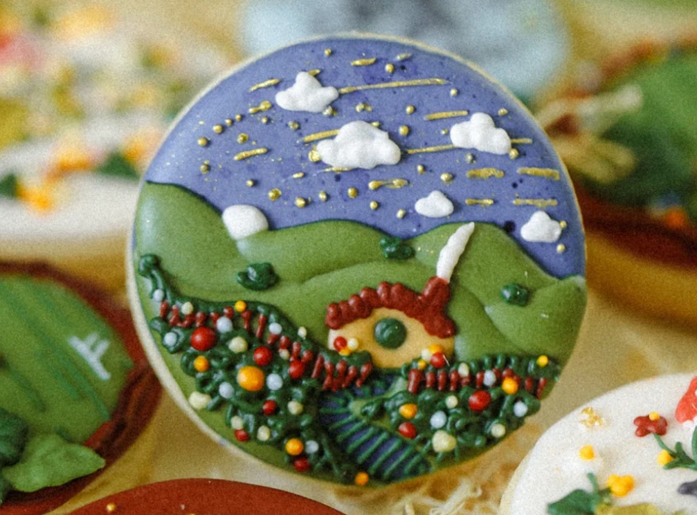 A house and mountain scene painted on a cookie.