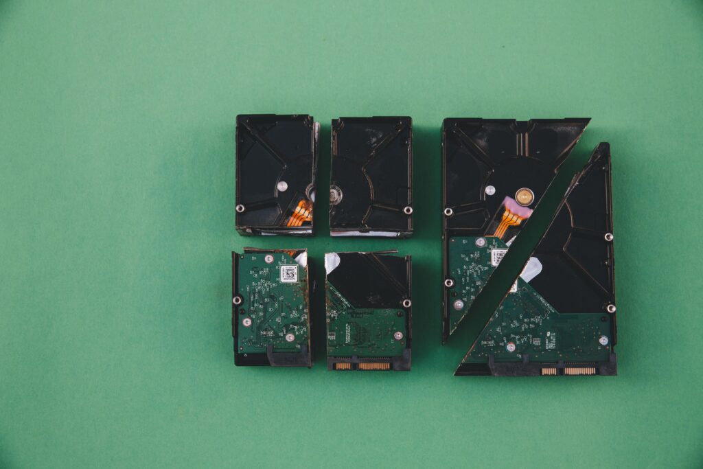 Four computer hard drives cut into pieces, arranged neatly on a green background.