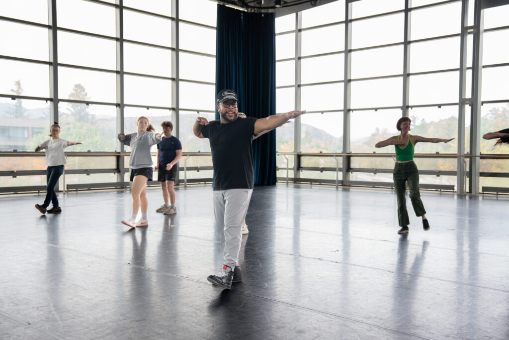 A group of dancers in a beautiful room of windows.
