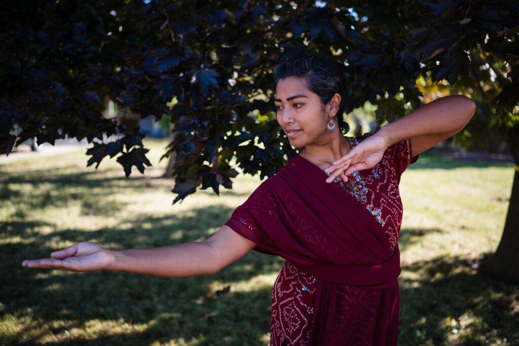 A woman with a medium skin tone moves her arms outside.