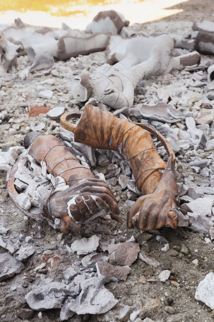 A bronze arm breaks free of a clay cast.