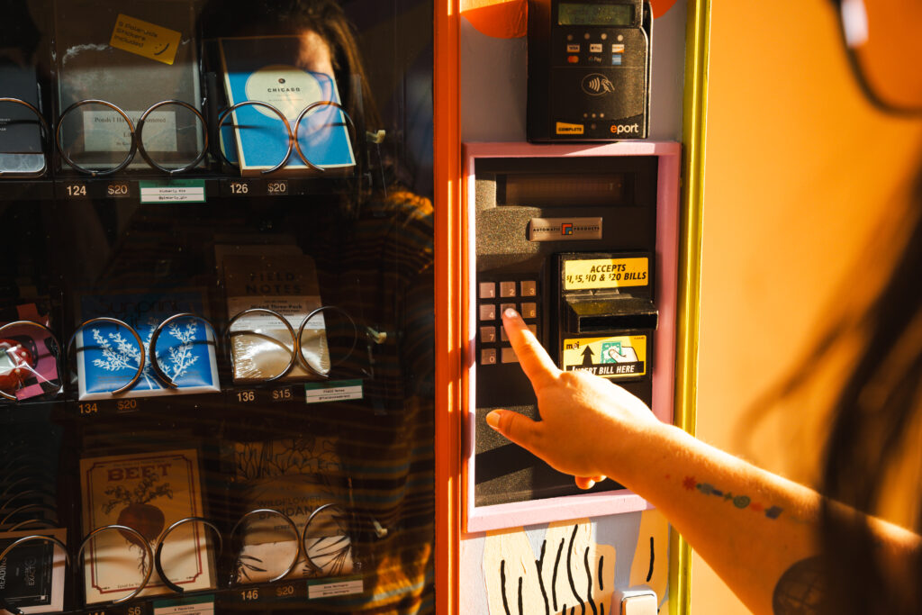 A person with light skin reaching for a vending machine.