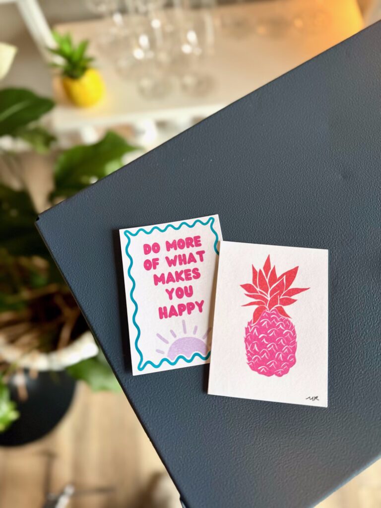 Two small art prints, one of a pink pineapple and the other reading: DO MORE OF WHAT MAKES YOU HAPPY.