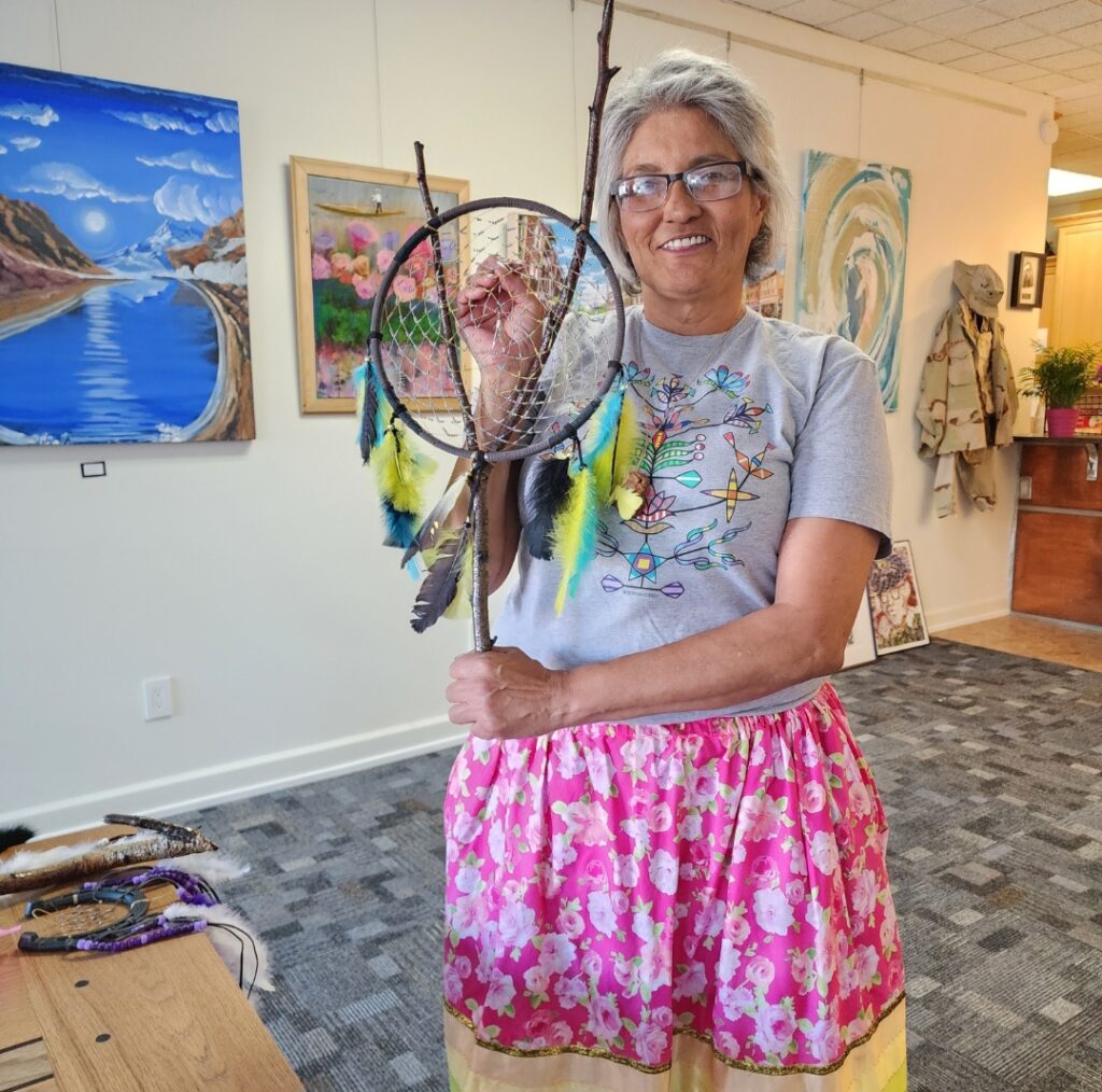Woman holding dreamcatcher in brightly lit gallery