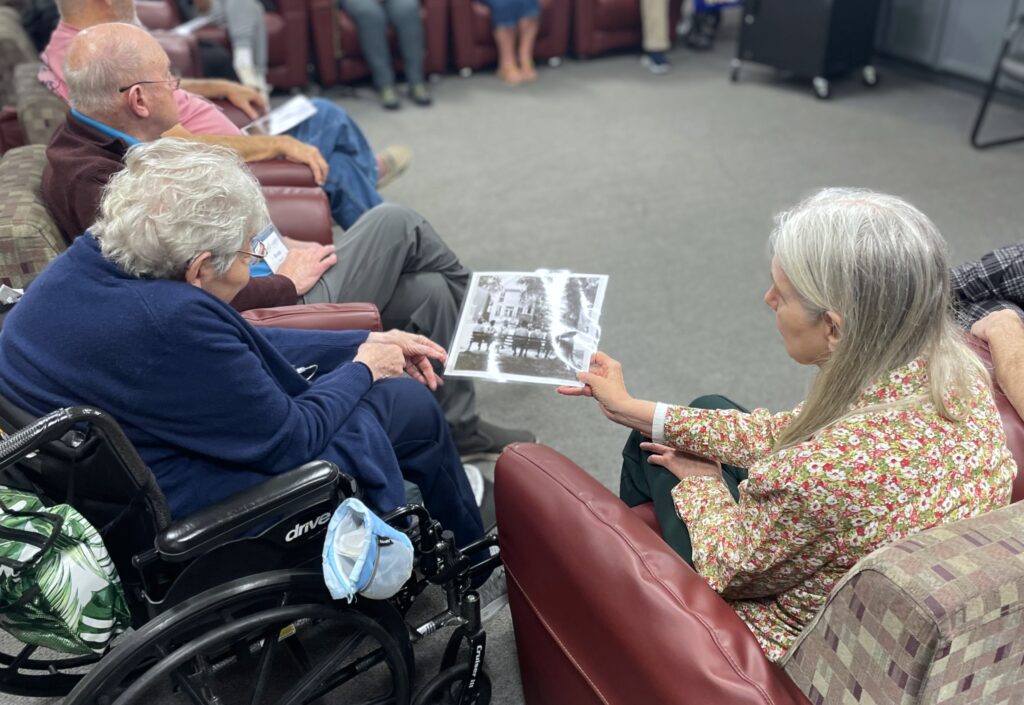 Two people passing around a black and white image while sitting dow.