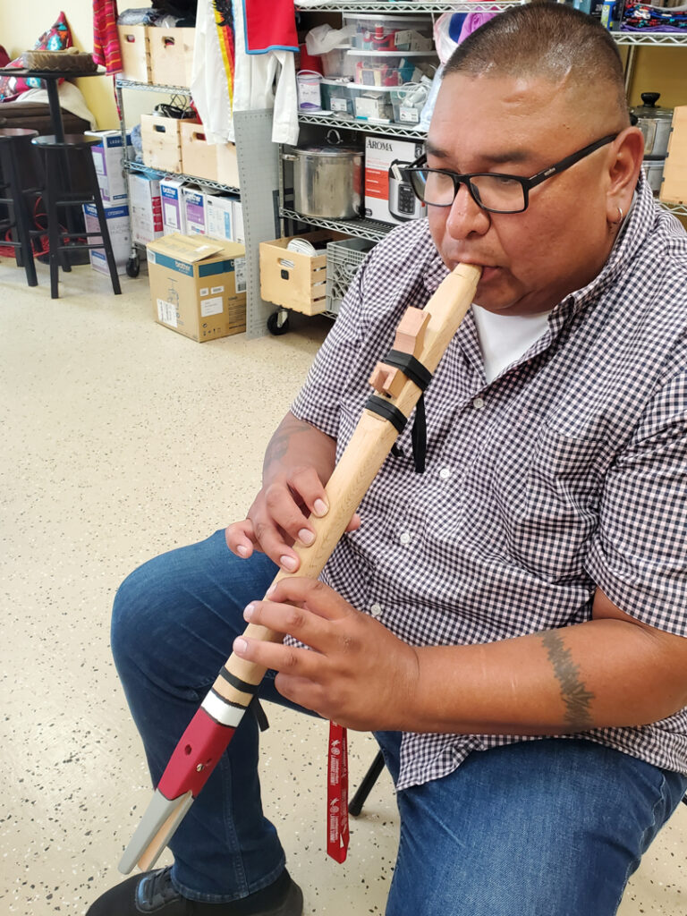 A person playing a wooden, hand-carved flute