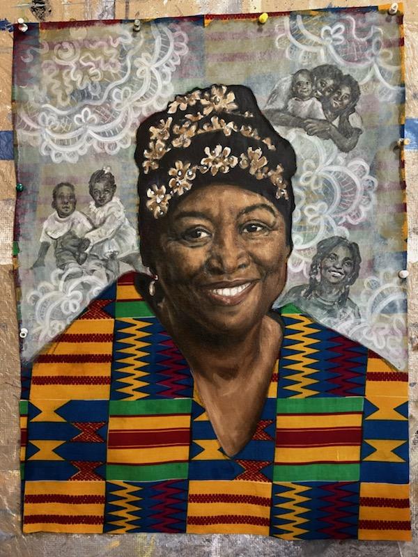 A vertical quilt pinned to a surface with a woman's portrait.