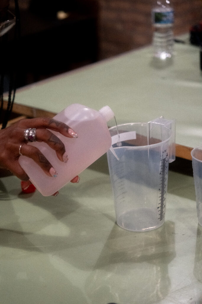 A hand pouring liquid into a measuring cup.