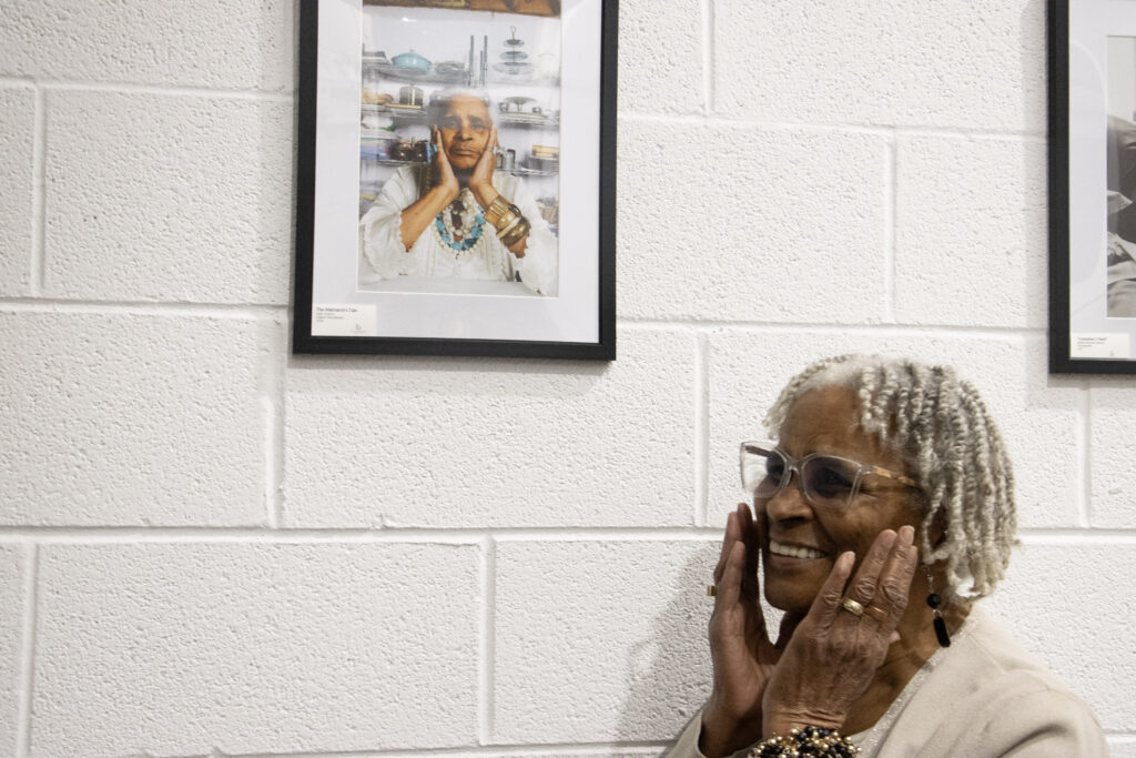 A woman with dark skin smiling with her hands to her cheeks.